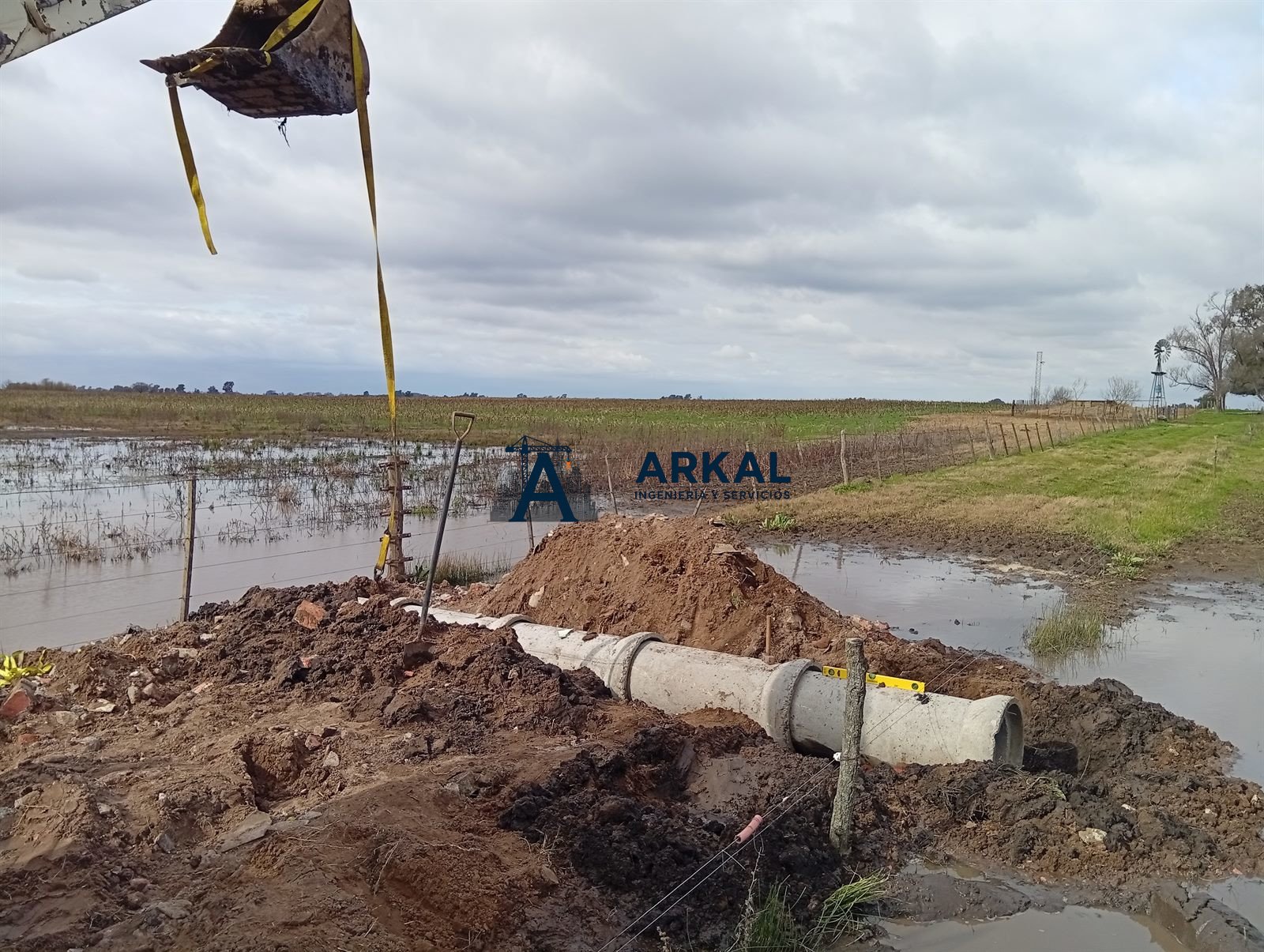 Retroexcavadora bajando un caño de hormigón para la alcantarilla