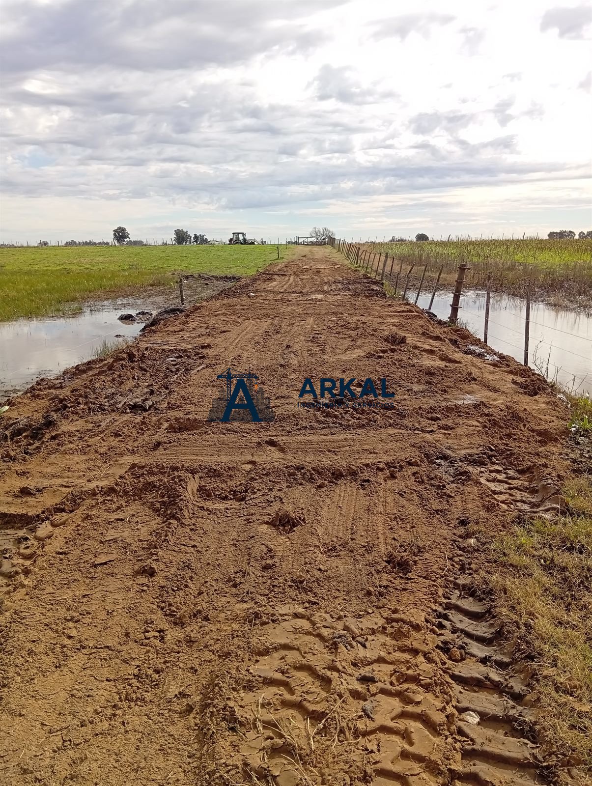 Entrada de campo elevada sobre terraplén de tierra, transitable con el campo anegado